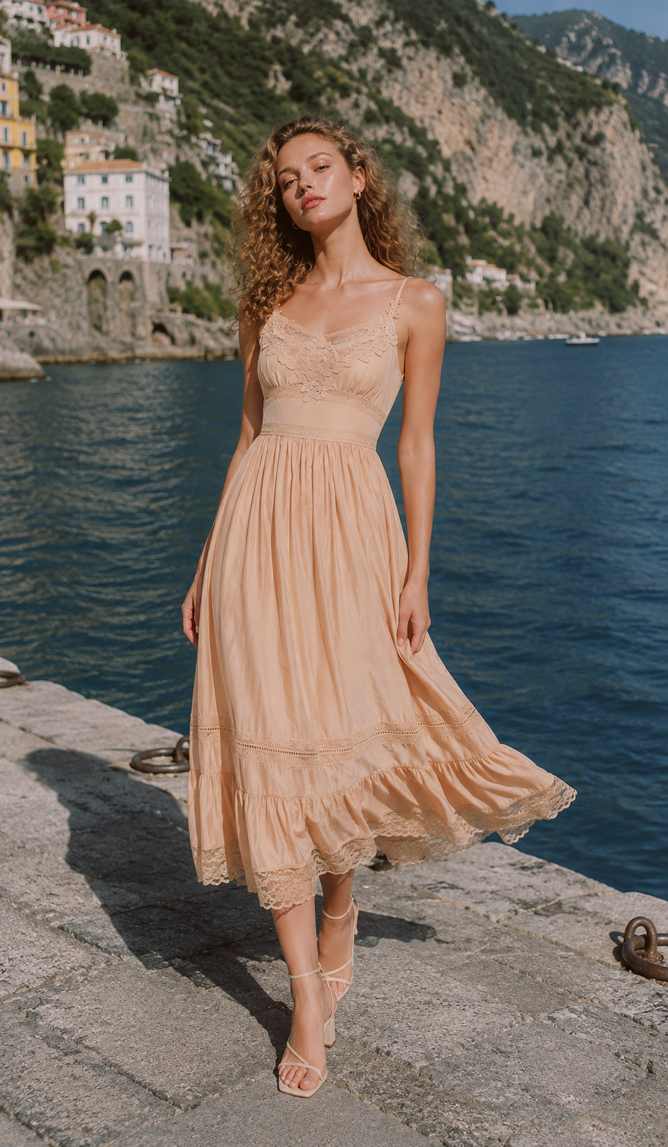 Model wearing the Champagne At Sunset Dress on the Amalfi Coast, featuring a romantic champagne midi dress with lace bodice, flowing skirt, and elegant feminine silhouette.