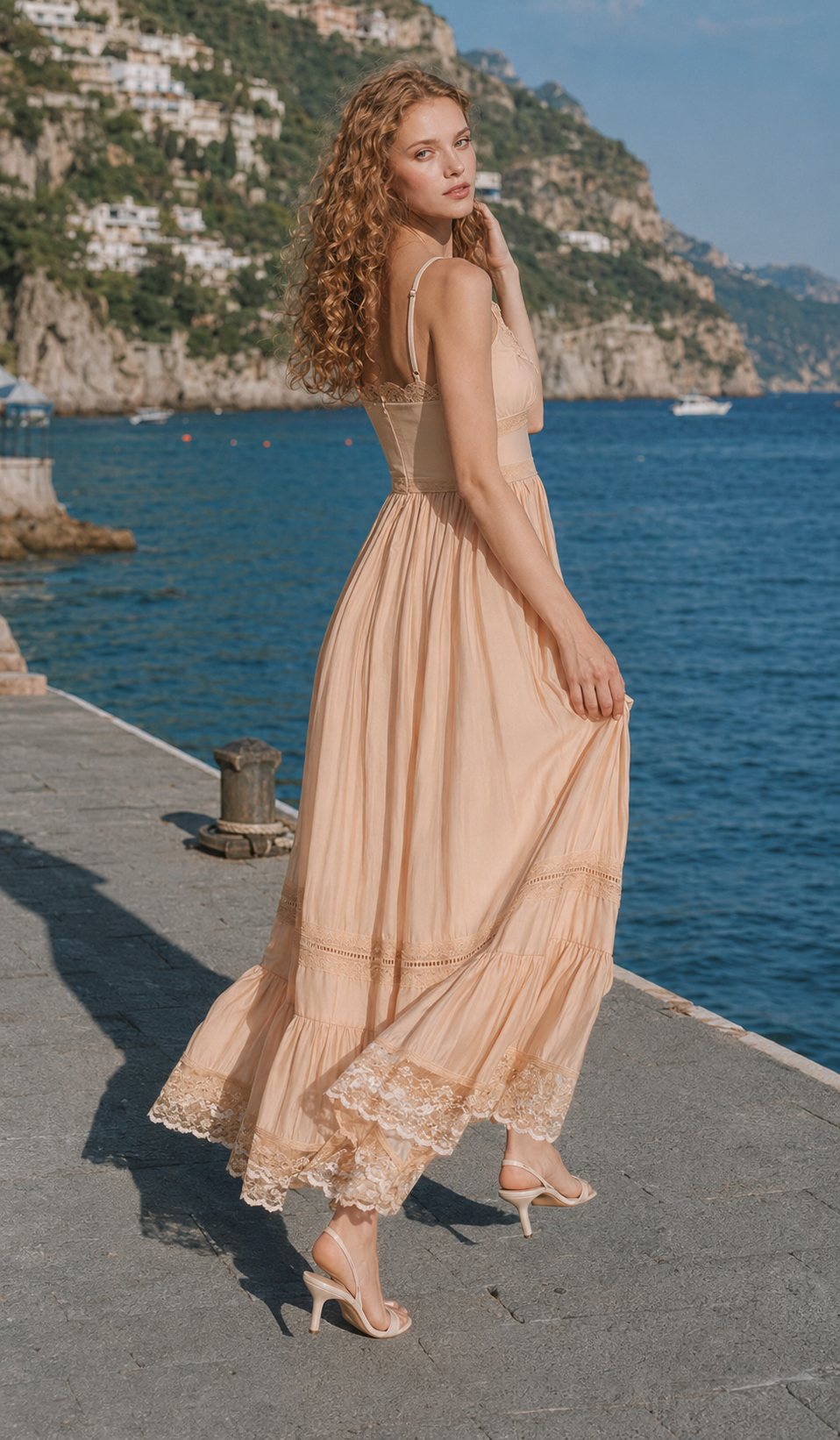 Back view of the Champagne At Sunset Dress featuring adjustable spaghetti straps, fitted waist, and flowing lace-trimmed midi skirt by the Mediterranean coast.