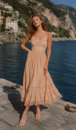 Model posing by the seaside in the Champagne At Sunset Dress, showcasing the delicate floral lace bodice, soft champagne fabric, and graceful summer style.