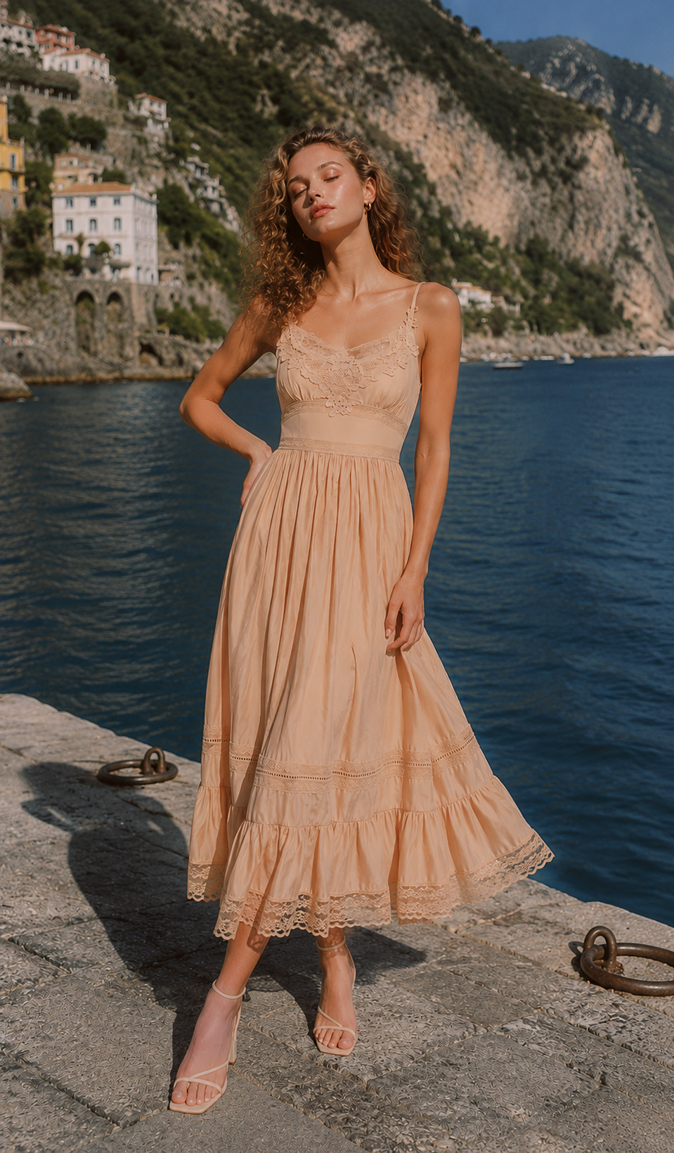 Model posing by the seaside in the Champagne At Sunset Dress, showcasing the delicate floral lace bodice, soft champagne fabric, and graceful summer style.