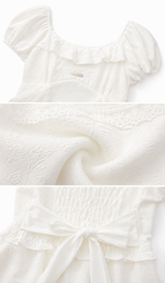 Close-up details of the Château Diary Dress showcasing the textured floral fabric, delicate ruffle trim, smocked back, and elegant waist bow.