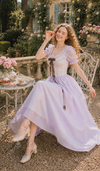 Front view of the Letters From Villa Fiora Corset Dress featuring a soft lavender chiffon skirt, lace corset bodice, puff sleeves, and romantic floral villa backdrop.