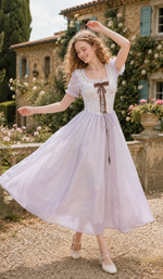 Lifestyle image of the Letters From Villa Fiora Corset Dress with a straw hat, highlighting the elegant corset bodice, airy skirt, and romantic Italian garden setting.