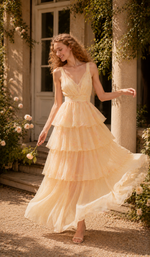 Model posing outdoors in the Lilies Before Sunset Dress with layered chiffon ruffles, flattering V-neckline, and romantic floral design inspired by an English garden.