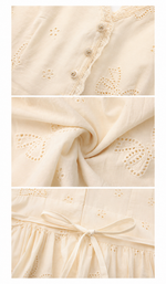 Close-up detail of The Cream Memory Dress featuring floral embroidery, lace-trimmed neckline, decorative buttons, soft fabric texture, and waist tie craftsmanship.