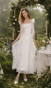 Woman wearing The Rose Oath Dress in white, standing under a rose-covered garden arch with romantic ruffle details.