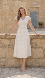 Front view of The Rosekeeper of Gordes Dress with a V-neckline and puff sleeves on a Provence stone terrace.